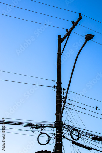 Many wires attached to the electric pole, the chaos of cables and wires on an electric pole, blue sky background, technological combination concept in Brazil