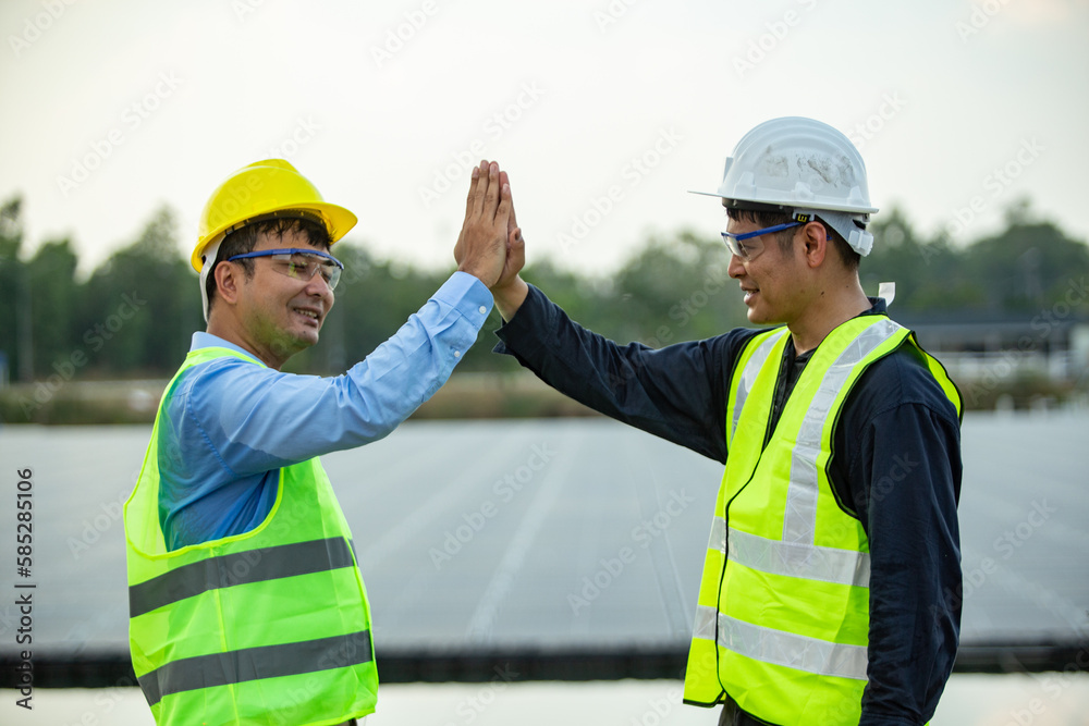 Engineer and technician giving high five to each other at solar power plant Engineer and technician giving high five to each other at solar power plant