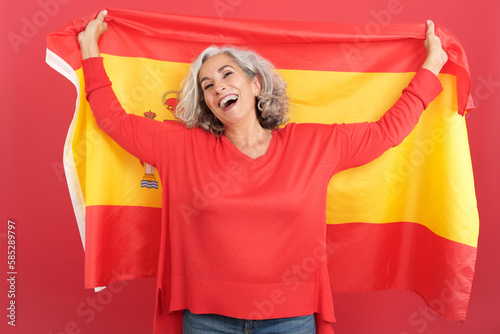 Happy mature woman raising a spanish national flag