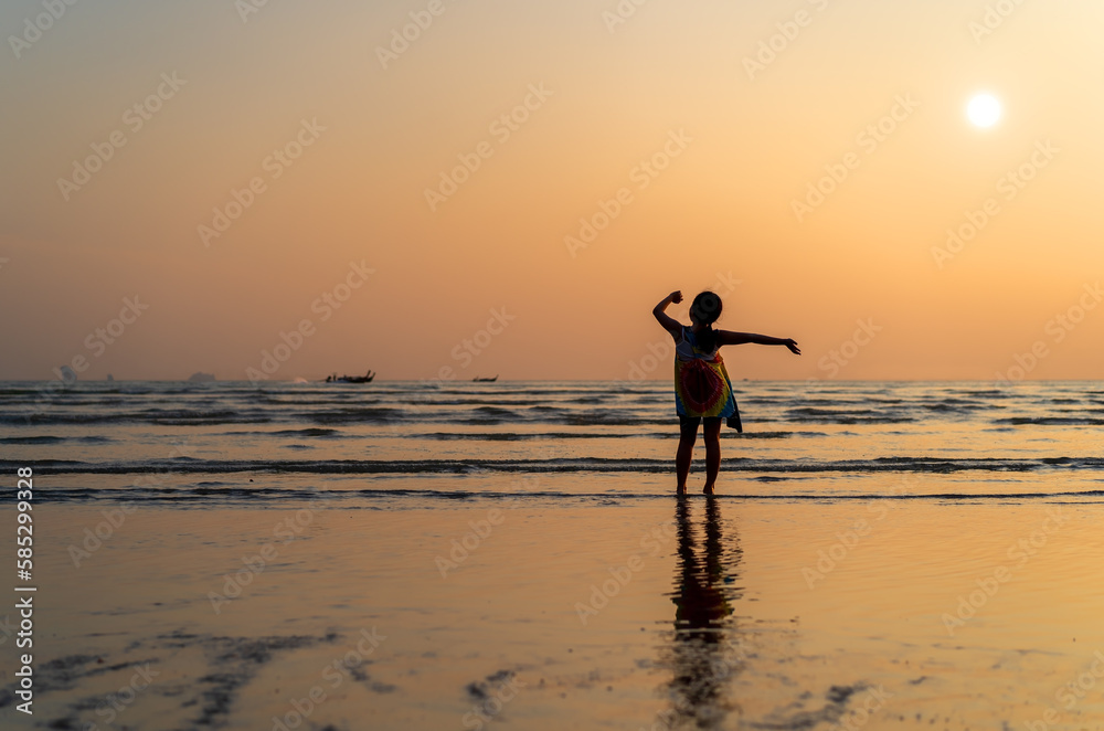 back asian child or kid girl standing on summer sand beach or sea and happy raising hands with golden warm sunlight on sunset twilight or morning sunrise for family vacation travel on holiday relax