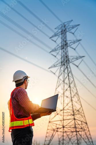 Bild auf Leinwand Asian electrical engineers checking location using a notebook computer standing at a power station to view the planning work by producing electrical energy at high voltage electrodes