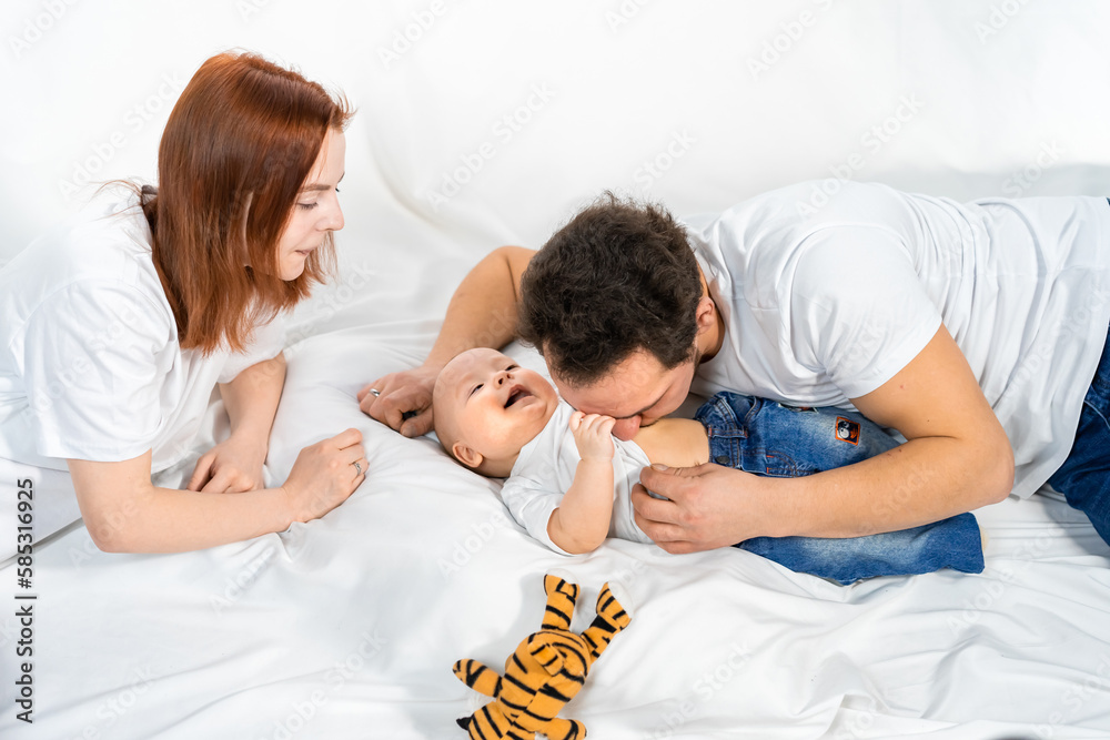 Fototapeta premium family with a child. Happy family is sitting on the floor. Father, mother and child have fun together. minimalist interior