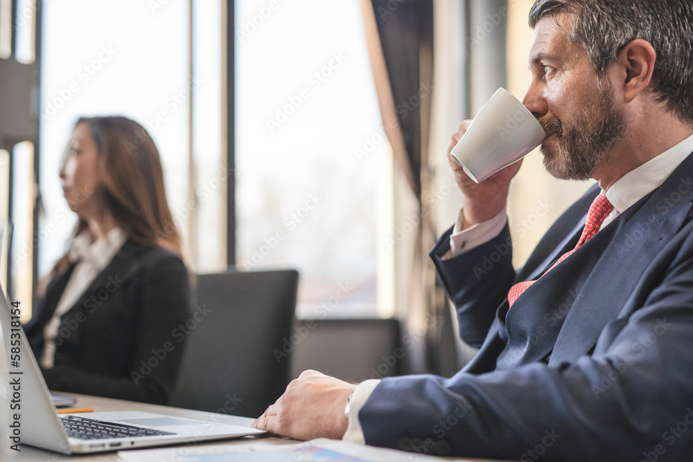 Fototapeta premium Middle-aged businessman drinking American coffee while during meeting in the office