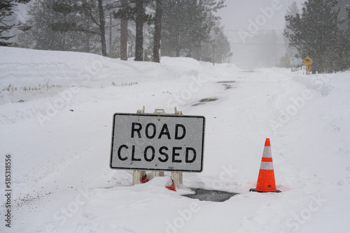 Road closed sign on highway in Sierra Nevada mountains during strong winter storm.