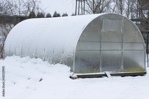 Close-up of a polycarbonate arched greenhouse covered with snow in a winter garden