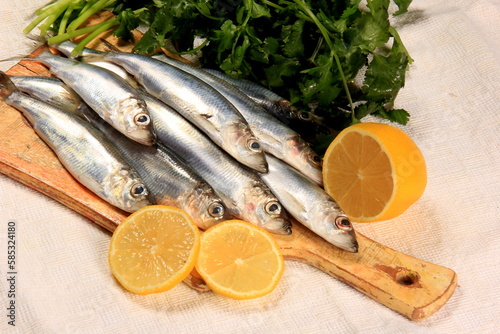 Fresh sardines with lemon and parsley on a wooden board. Fresh Baltic herring