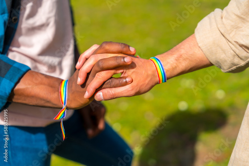 Hands of a multiethnic gay male couple holding hands, lgbt concept, homosexual guys