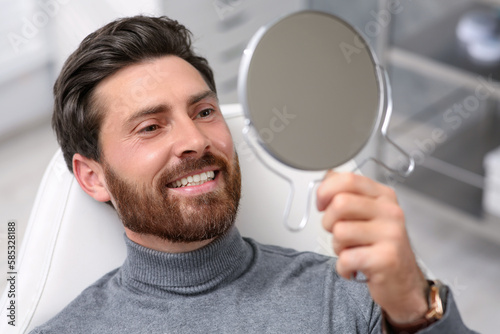 Man looking at his new dental implants in mirror indoors