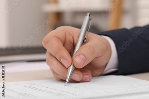 Man signing document at table, closeup view