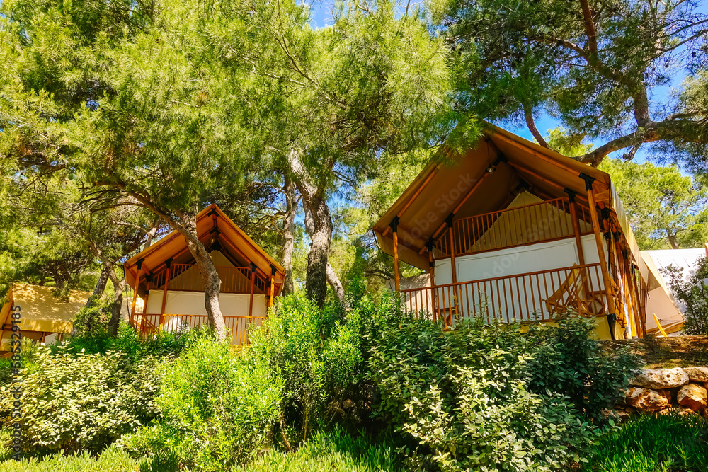 Gorgeous view of canvas glamping bell tents in a green wood on a sunny day. Croatia, Europe. Gorgeous view of canvas glamping bell tents in a green wood on a sunny day. Croatia, Europe.