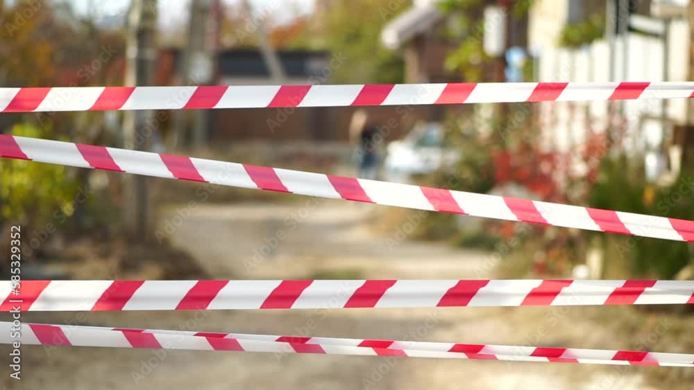 Red and white warning tape swinging in the wind. Protection sign. Don't cross the line. Red White caution tape pole fencing is protects for No entry. Backdrop without people, empty street. Red and white warning tape swinging in the wind. Protection sign. Don't cross the line. Red White caution tape pole fencing is protects for No entry. Backdrop without people, empty street.