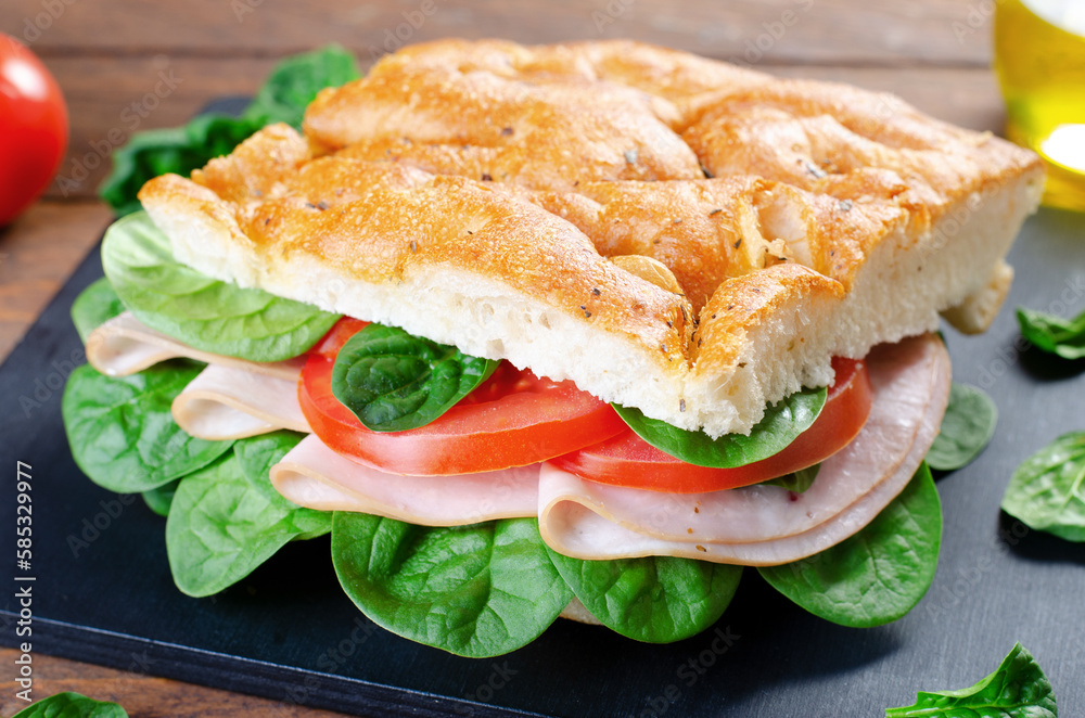 Focaccia Sandwich with Ham, Tomatoes, and Spinach, Sandwich with Italian Flat Bread on Wooden Background Focaccia Sandwich with Ham, Tomatoes, and Spinach, Sandwich with Italian Flat Bread on Wooden Background