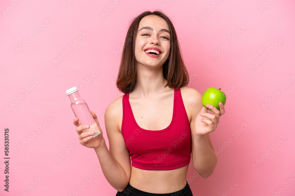 Young Ukrainian woman isolated on pink background with an apple and with a bottle of water Young Ukrainian woman isolated on pink background with an apple and with a bottle of water