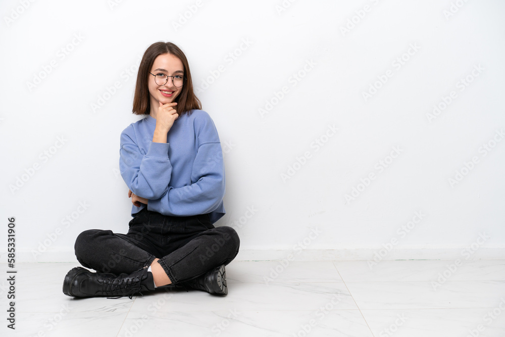Young Ukrainian woman sitting on the floor isolated on white background with glasses and smiling Young Ukrainian woman sitting on the floor isolated on white background with glasses and smiling