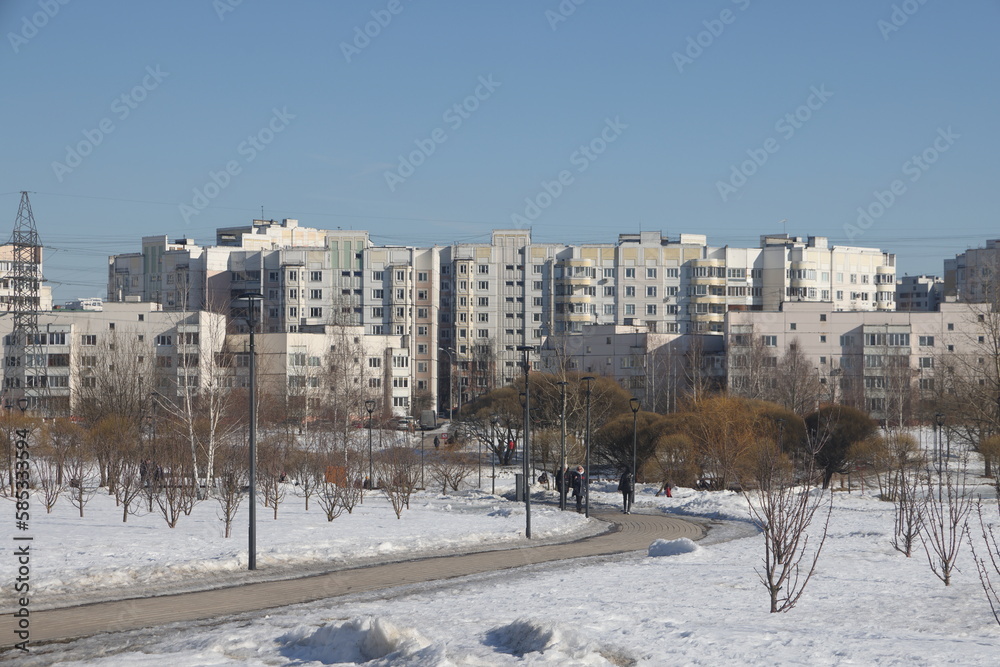 Landscapes in the park with melting snow, puddles and ice in spring. Residential buildings and spring landscapes of Butovo, Moscow, thawed patches, March 2023.