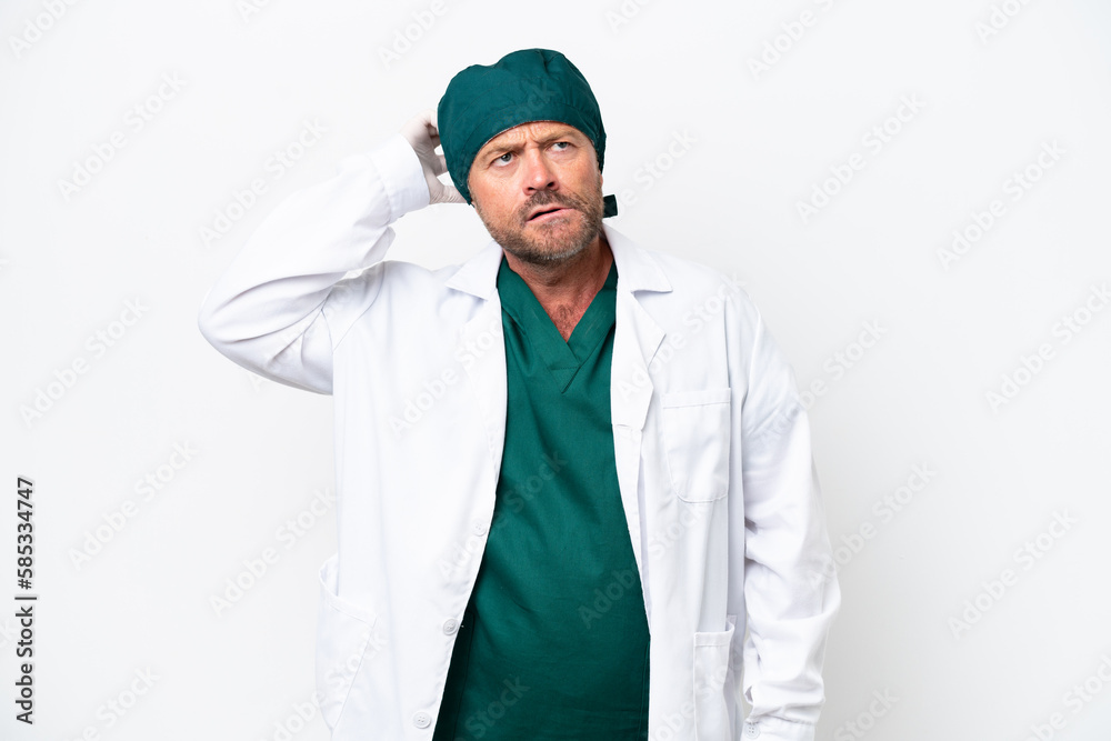 Middle age surgeon in green uniform isolated on white background having doubts and with confuse face expression
