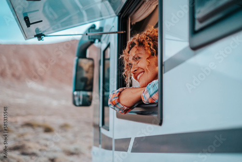 Travel and destination happiness concept lifestyle people. One serene woman smile and enjoy freedom and nature admiring outdoors inside her camper van motor home tiny house. Alternative lifestyle