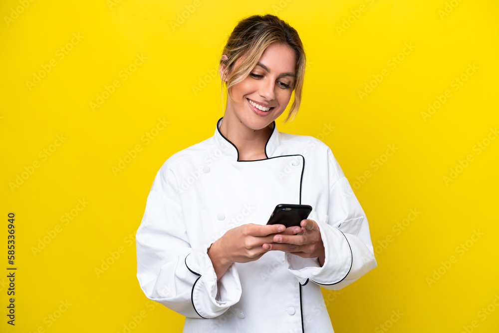 Uruguayan chef woman isolated on yellow background sending a message with the mobile Uruguayan chef woman isolated on yellow background sending a message with the mobile