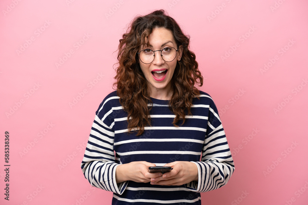 Young caucasian woman isolated on pink background surprised and sending a message Young caucasian woman isolated on pink background surprised and sending a message