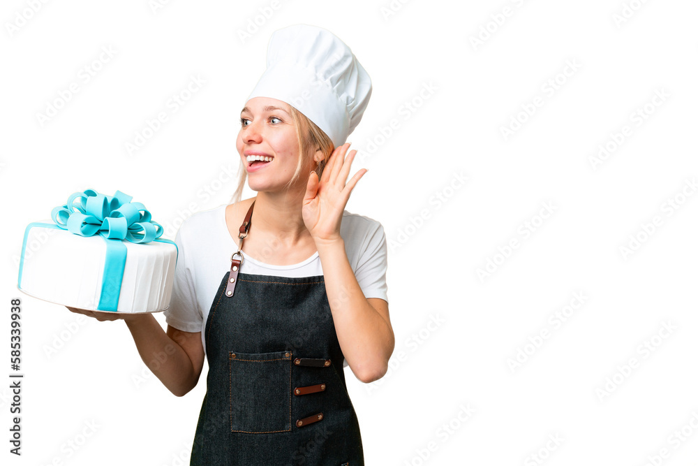 Young pastry blonde woman with a big cake over isolated chroma key background listening to something by putting hand on the ear Young pastry blonde woman with a big cake over isolated chroma key background listening to something by putting hand on the ear