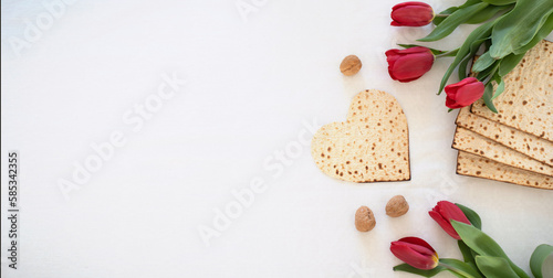 white big banner Matzah shape of heart with red tulips and walnut on white background. Traditional of Holiday on Passover. Home symbol of lovely Jewish family in pesach. top view.
