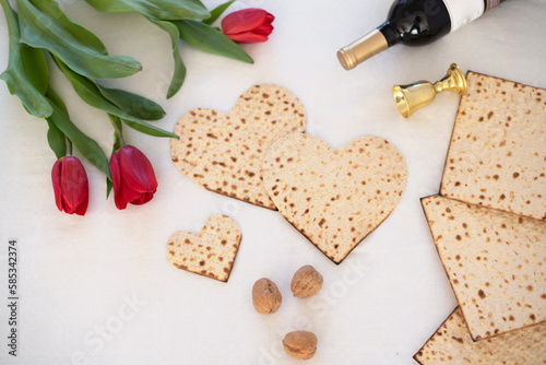 Matzah shape of hearts with red tulips, bottle of wine and walnut on white background. Traditional of  Holiday on Passover. Home symbol of lovely Jewish family in pesach. top view. © vera
