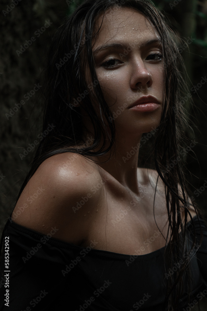 A beautiful tanned young woman with natural makeup and smooth hair stands in the jungle among exotic plants. A beautiful tanned young woman with natural makeup and smooth hair stands in the jungle among exotic plants.