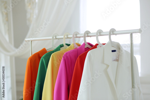 Obraz na płótnie Multi-colored bright jackets on a hanger against the background of the room