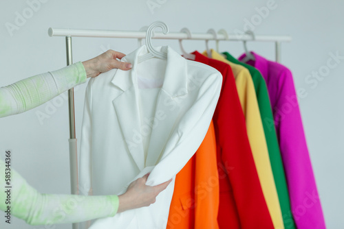 A woman's hands chooses clothes on a hanger on a white background.