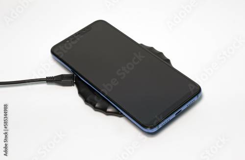 Smartphone lies on a wireless charger on a white background. Modern technologies of mobile devices