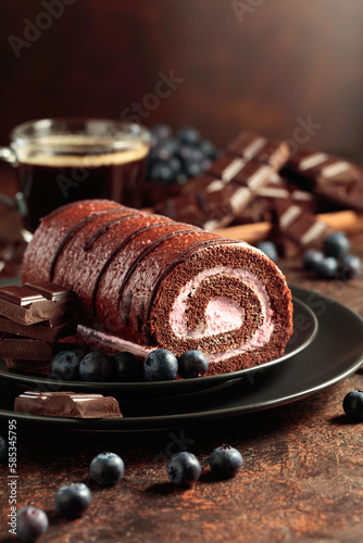 Chocolate roll cake with blueberries and a broken chocolate bar.