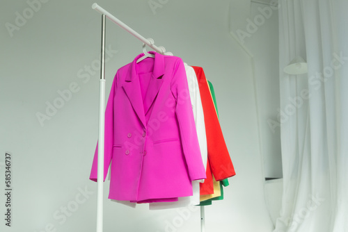 Multi-colored bright jackets on a hanger on a white background