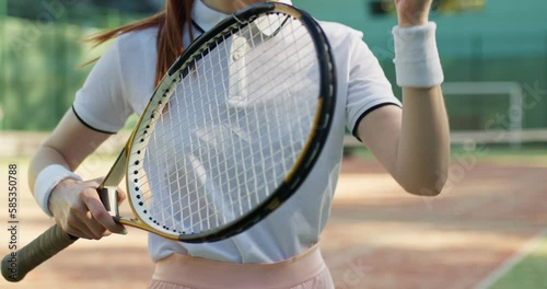 ginger slim girl holding racket in hands throws ball on the ground, catches it, close up cropped slow motion, sportswoman tossing the ball berore game, competition photo