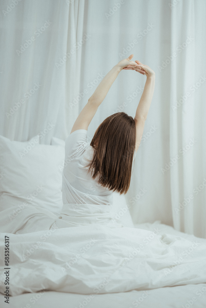 Top view of attractive young smiling woman smiling and stretching while lying on the bed at home Top view of attractive young smiling woman smiling and stretching while lying on the bed at home