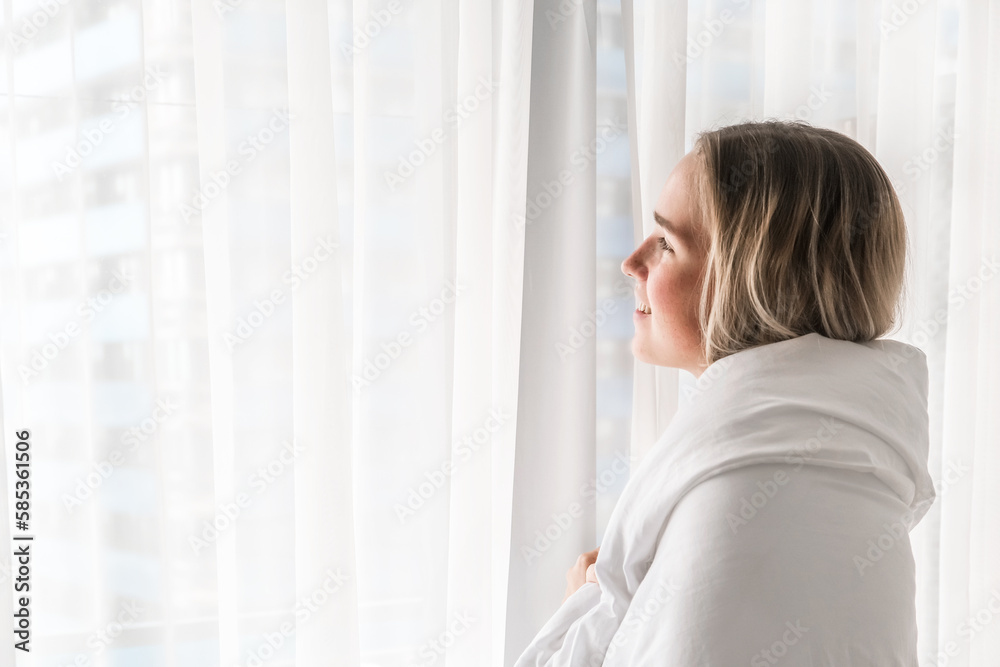 Concentrated beautiful girl sits and looks out the window at home. Woman sadly contemplatively looks out the window alone. Concentrated beautiful girl sits and looks out the window at home. Woman sadly contemplatively looks out the window alone.
