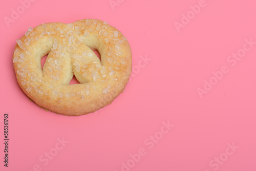 Kruche słodkie ciasteczko posypane cukrem leżące na różowym tle