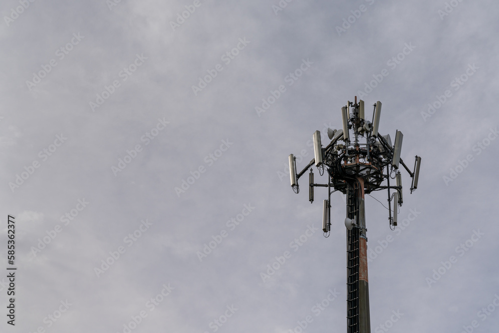 close-up view of a cellphone and internet 5G antenna with overcast sky copy space