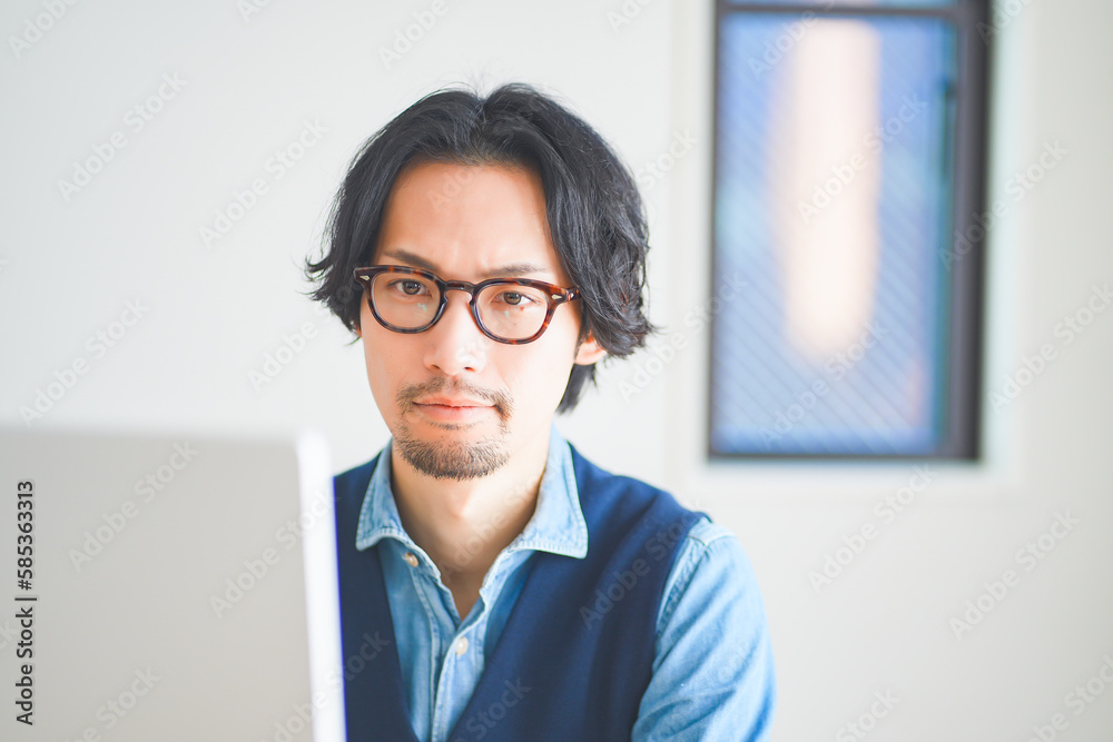 パソコンに向かって考え事をする若い男性 パソコンに向かって考え事をする若い男性