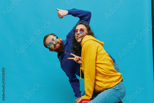 Woman and man smile sitting on suitcase with red suitcase smile, on blue background, packing for trip, family vacation trip.
