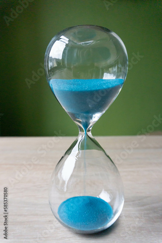 Hourglass with azure sand on wood 