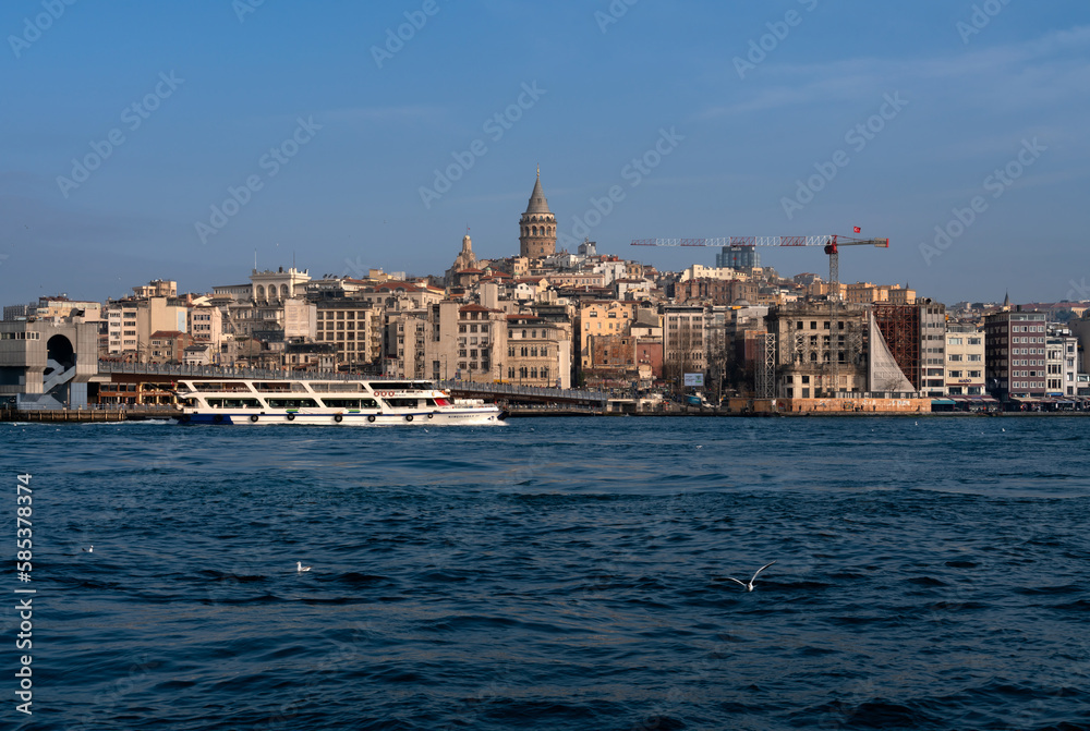 View of Beyoglu district with Galata Tower and Galata Bridge in the foreground from the waters of the Golden Horn Bay on a sunny day, Istanbul, Turkey