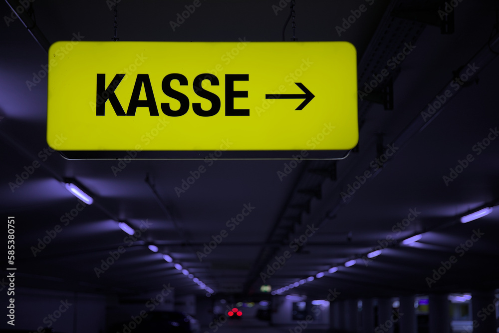Yellow glowing KASSE information sign in an underground car park with white neon lighting Yellow glowing KASSE information sign in an underground car park with white neon lighting