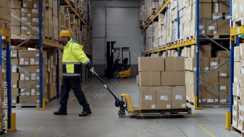 Male warehouse worker dragging a pallet truck.