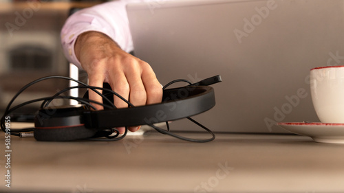 man's hand picking up the headphones from behind the computer