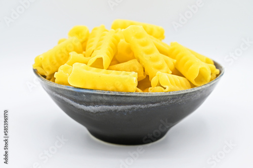 Festonati pasta in a dark grey bowl, isolated on a white background