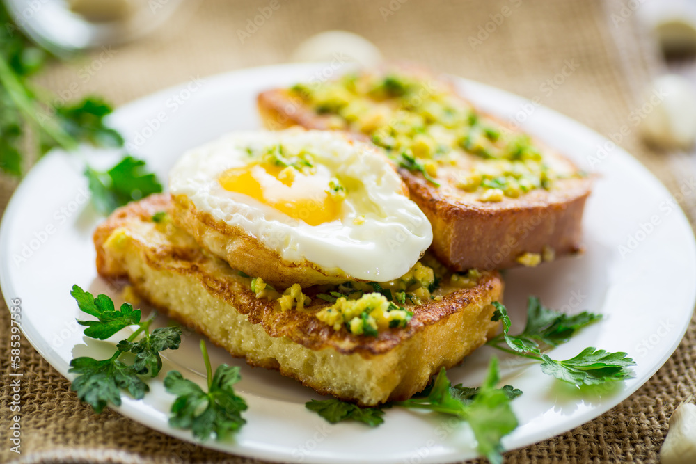 Fried croutons in batter with garlic and herbs and a fried egg in a plate.