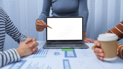 Fotografie White blank screen laptop for mock up, small business accounting team meeting three asian people with salary monthly charts data, basic business accounting and bookkeeping concept