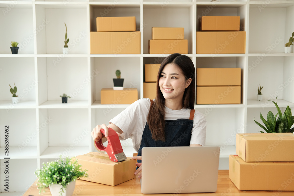 Startup small business, Young Asian woman owner using adhesive tape, packing carton parcel box working at the home office, seller prepares the delivery. Startup small business, Young Asian woman owner using adhesive tape, packing carton parcel box working at the home office, seller prepares the delivery.