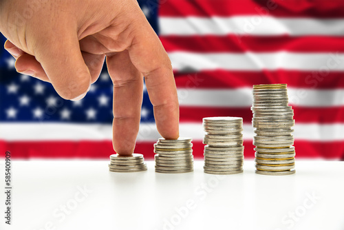 banknotes and coins in front of the national flag of USA united states of america stack of silver and gold coin and hand gestures are walking for business concept. photo