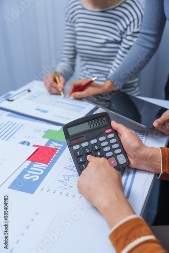 Obraz na plátně Using calculator, small business accounting team meeting three asian people with salary monthly charts data, basic business accounting and bookkeeping concept